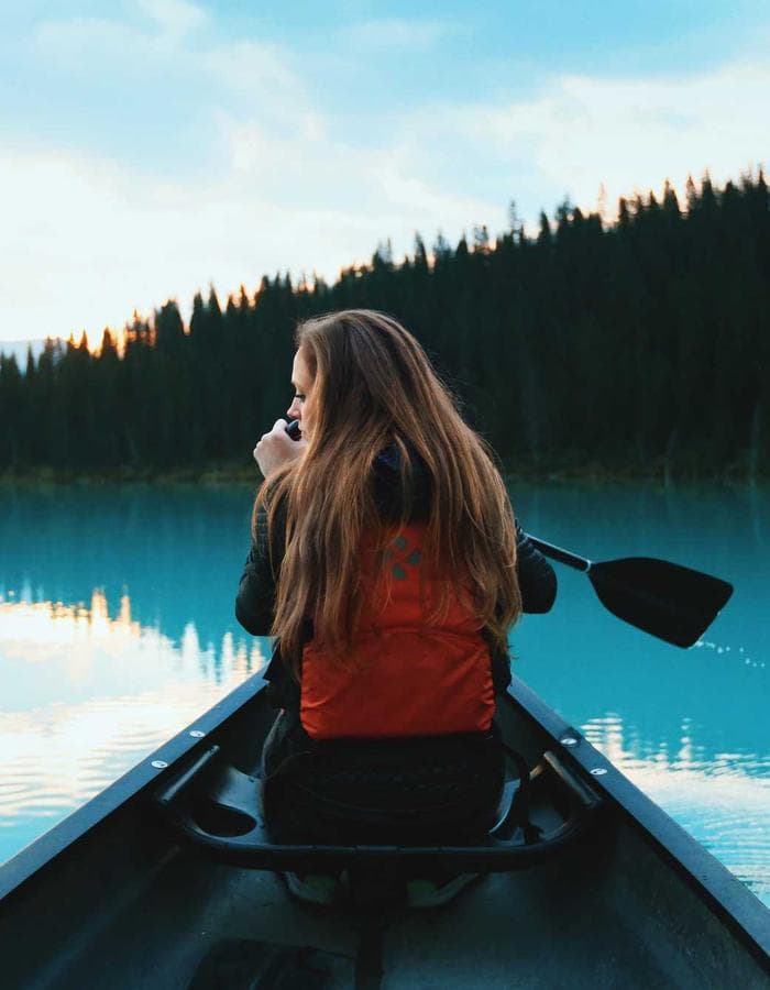 Woman paddling a canoe across a still lake