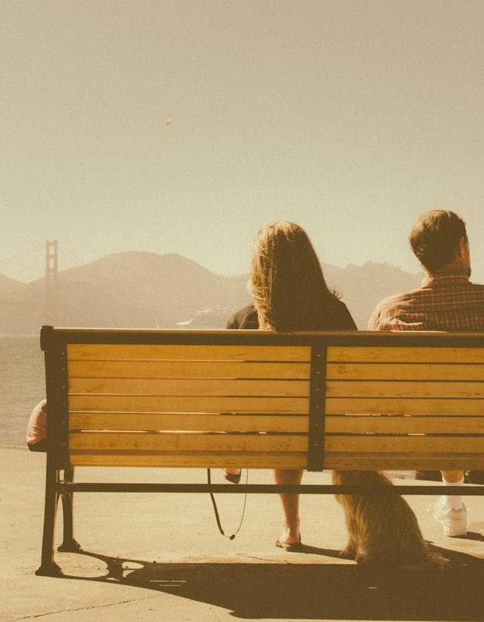 Couple sitting together on a bench at sunset